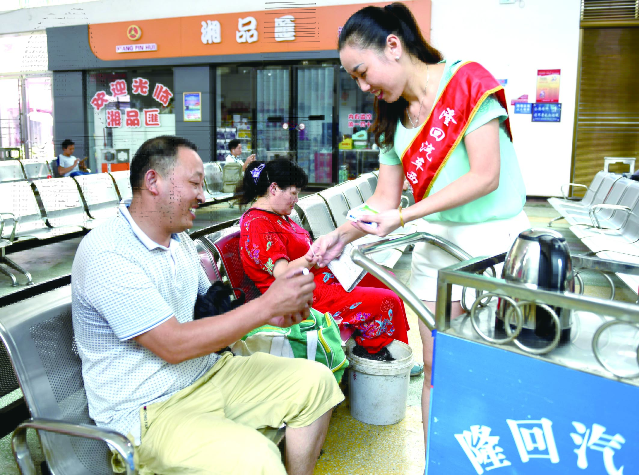 隆回分公司汽車西站工作人員正在為旅客免費贈送藿香正氣水。