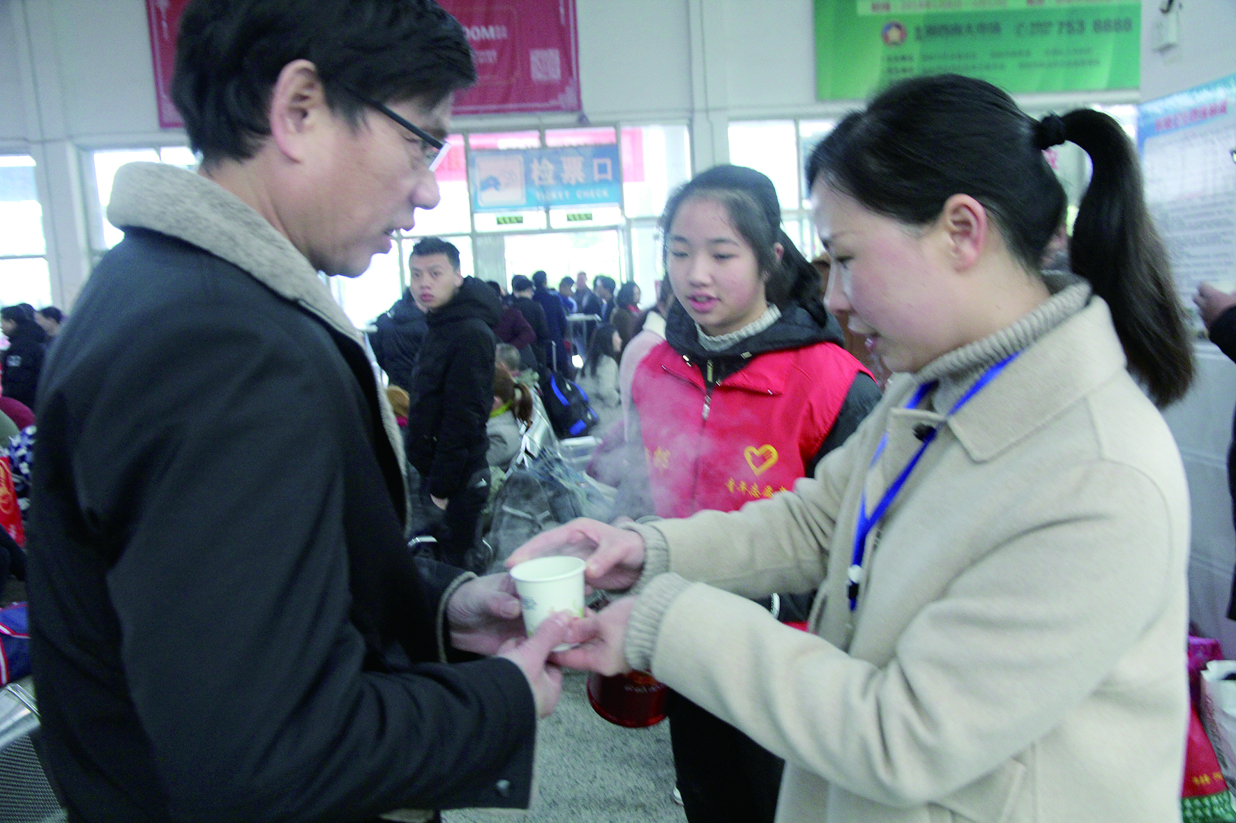 母女服務(wù)春運(yùn) 2月13日，記者在新邵分公司汽車站看到，該分公司安全科副科長李喜梅與其在新邵一中初中部1701班就讀女兒劉嘉怡在車站擔(dān)當(dāng)志愿者。李喜梅在候車室耐心為旅客釋疑解惑，劉嘉怡為旅客遞上一杯杯熱茶，有時(shí)母女也相互合作，其樂融融。 祖冠 攝影報(bào)道
